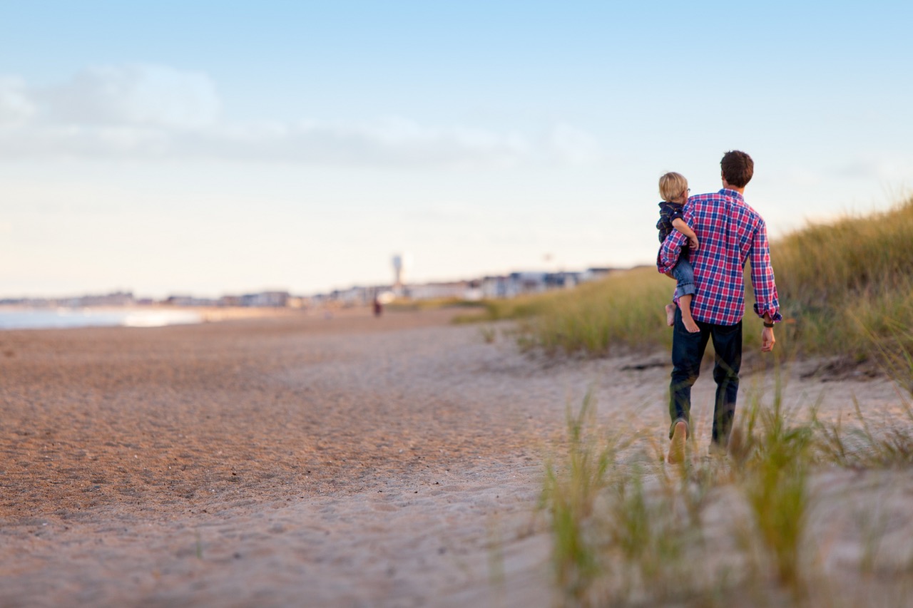 man boy on beach holding a little boy